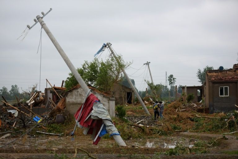 Residents walk amongst the rubble of destroyed houses after a tornado in Funing, Yancheng