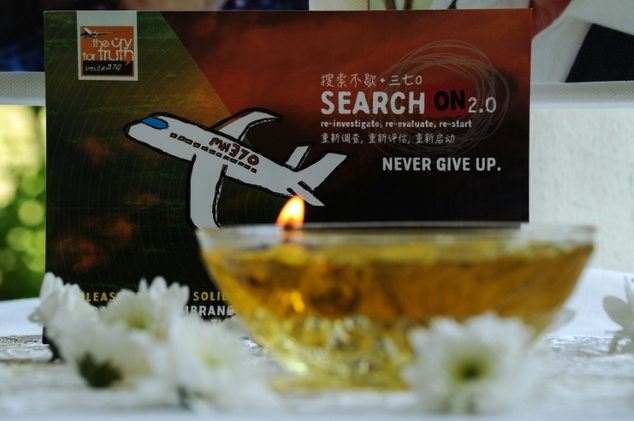 A candle burns a prayer message for passengers of missing Malaysia Airlines flight MH370 in Petaling