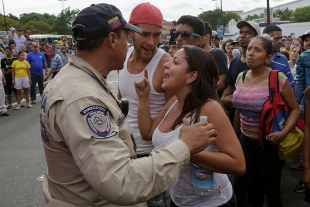 A woman argues with a riot police officer during a protest over food shortage 