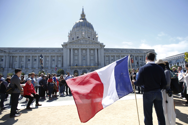A supporter for victims of the attack in Nice, France holds a French flag during a vigil and moment of silence in front of City Hall in San Francisco