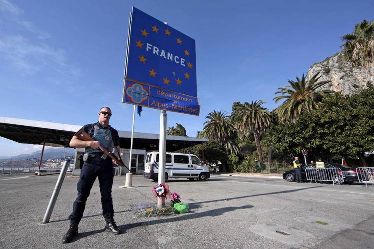 An armed French police officer stands guard at the Franco-Italian border to check vehicles