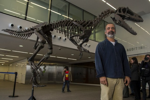 Argentine paleontologist Sebastian Apesteguia poses in Buenos Aires on July 13, 2016 next to a replica of Gualicho, an unusual new theropod dinosaur with a didactyl manus from the Upper Cretaceous that lived 90 million years ago found in the province of Rio Negro, in Argentina's Patagonia.  / AFP PHOTO / EITAN ABRAMOVICH