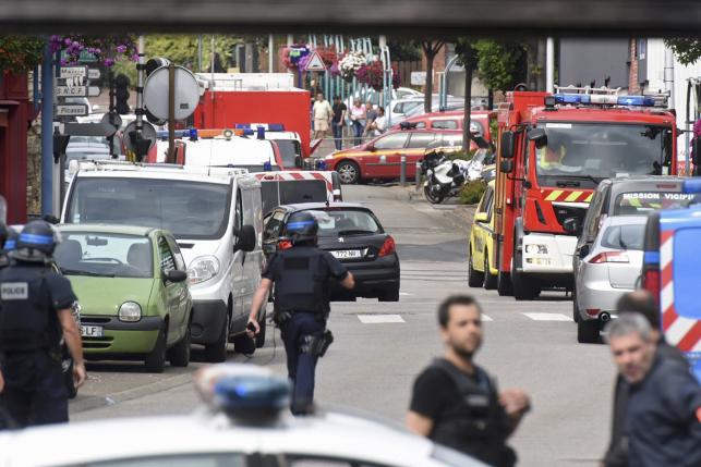Police and rescue workers stand at the scene after two assailants had taken five people hostage in the church at Saint-Etienne-du -Rouvray near Rouen in Normandy
