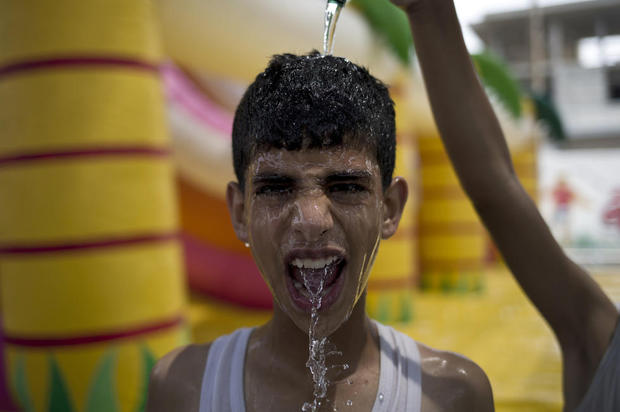 A Palestinian boy reacts as hir friends splashes his with water on his head during summer activities organized by the United Nations Relief and Works Agency (UNRWA) in Gaza City on August 3, 2015, during a sweltering heat wave
