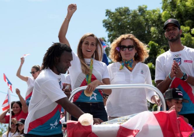 Tennis player and gold medallist Monica Puig (2nd L) greets the crowd while riding on a bus with wrestler Jaime Espinal (L),  President of the Olympic Committee of Puerto Rico Sara Rosario (2nd R) and athlete Javier Culson during a welcome ceremony in San Juan, Puerto Rico, August 23, 2016.  REUTERS/Alvin Baez