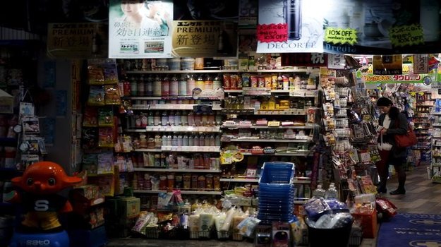 A shopper queues to pay at the cashier inside a discount drug store at a shopping district in Tokyo, Japan