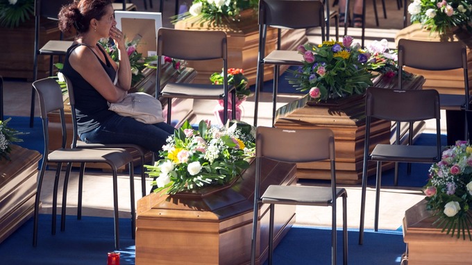 A woman sits next to a coffin to pay her respects as she attends a funeral for the earthquake victims