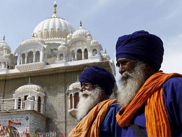 2 Sikh men standing in front of a monument in India