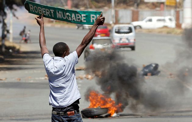 A man carries a street sign as opposition party supporters clash with police in Harare