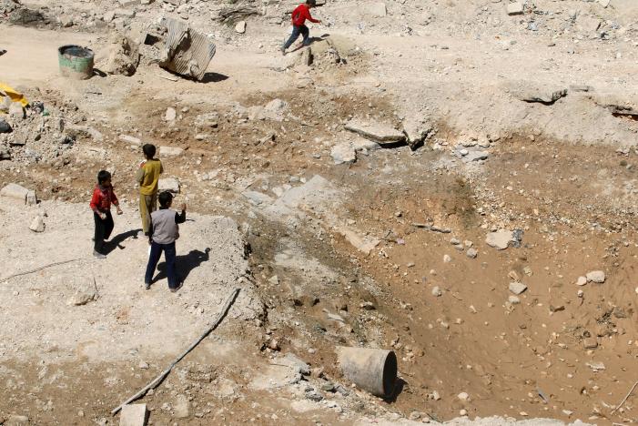 Boys stand near a crater at a damaged site in a rebel held area of Aleppo, Syria September 25, 2016. REUTERS/Abdalrhman Ismail