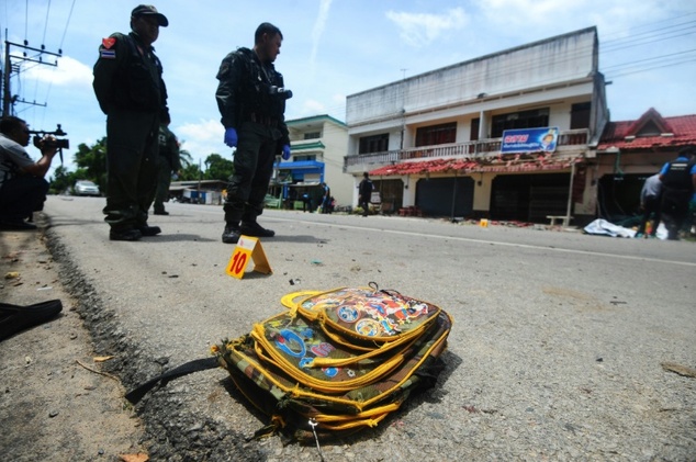 A child's backpack lies on the ground as a bomb squad inspects the site of a blast outside a school in Tak Bai district in the southern Thai province of Narathiwat