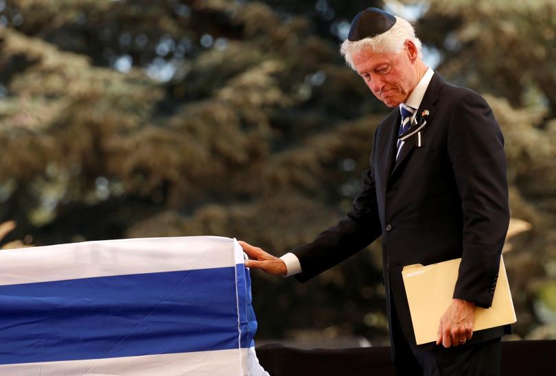 Former U.S. President Bill Clinton touches the flag-draped coffin of former Israeli President Shimon Peres, after eulogising him during his funeral ceremony at Mount Herzl cemetery in Jerusalem