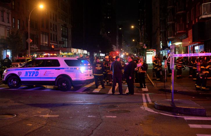 New York City police and firefighters stand near the site of an explosion in the Chelsea neighborhood of Manhattan, New York