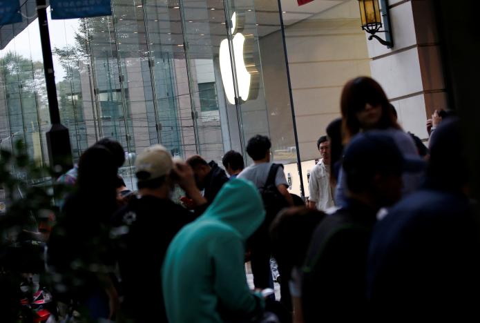 People sit in queue for the release of Apple's new iPhone 7 and 7 Plus in front of the Apple Store in Tokyo's Omotesando shopping district, Japan 