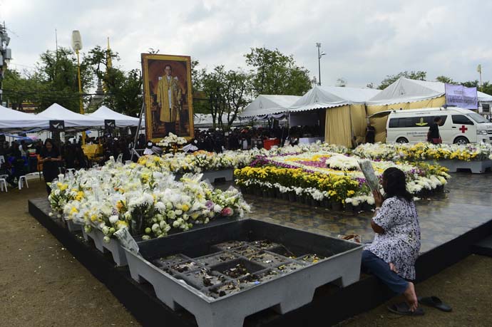 A woman pays respect to a portrait of late Thai King Bhumibol Adulyadej near the Grand Palace in Bangkok