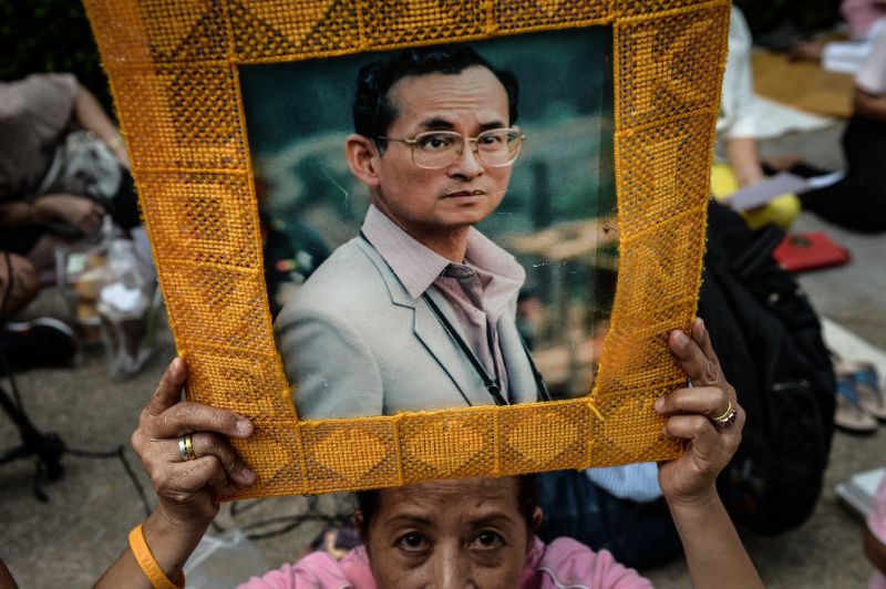 A Thai woman holds a picture of King Bhumibol Adulyadej at Bangkok's Siriraj Hospital, where the king is being treated