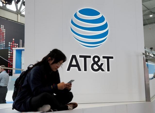 A woman looks at her mobile next to AT&T logo during the Mobile World Congress in Barcelona, Spain
