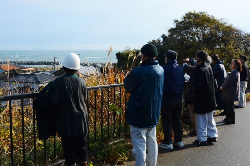 Local residents look out to sea from higher ground after evacuating their homes following a 6.9 magnitude earthquake and tsunami alert in Iwaki, Fukushima prefecture