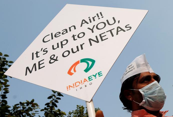 A man holds a placard during a protest against pollution in New Delhi, India