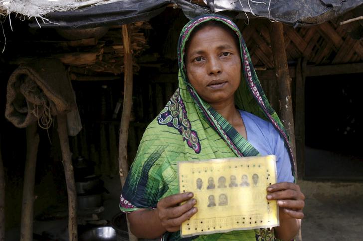 Rupban, a Rohingya woman, shows her ration card with pictures of her family members at a refugee camp in Kutupalong 